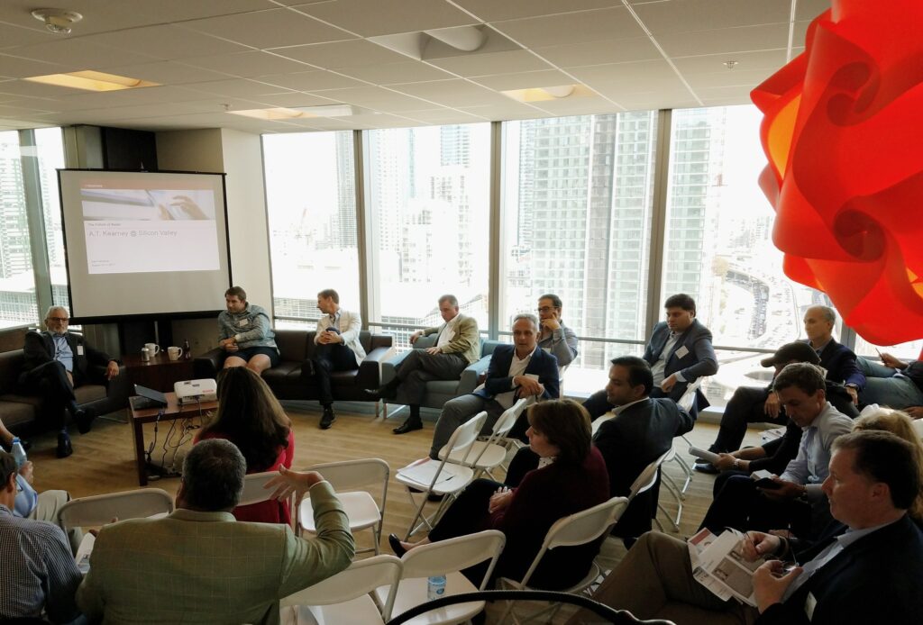 a conference room with people sitting in a circle watching a presentation